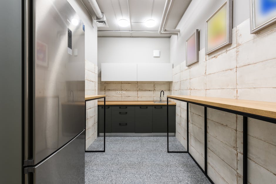 Interior of simple kitchen with new wooden counters and fridge in workplace designed in minimal style