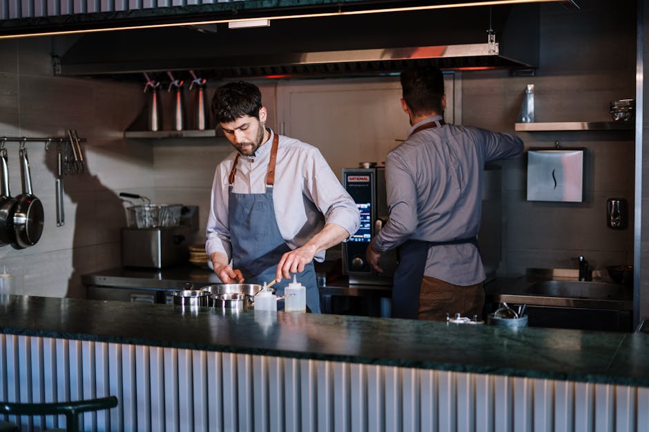 Two chefs working in an open kitchen, preparing dishes in a modern restaurant.